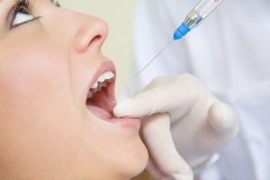 2796796 - dentist holding a syringe and anesthetizing his patient. close-up of mouth open